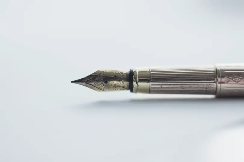 A gold fountain pen lying on a white surface