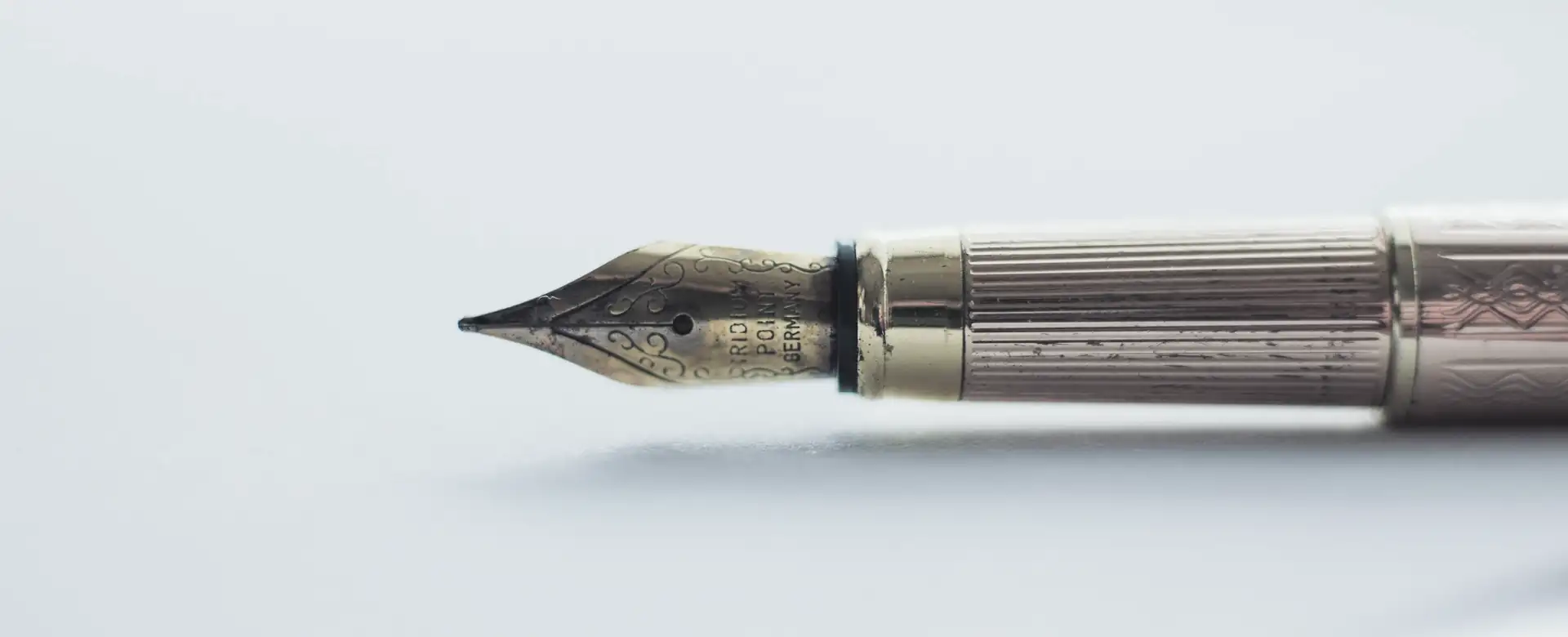 A gold fountain pen lying on a white surface