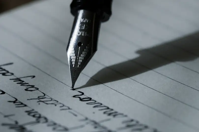 The nib of a fountain pen writing on lined paper