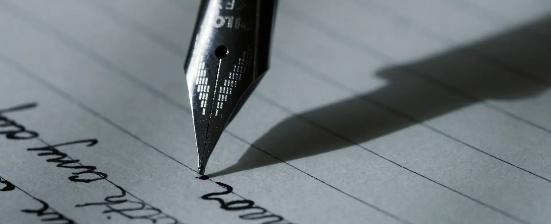 The nib of a fountain pen writing on lined paper
