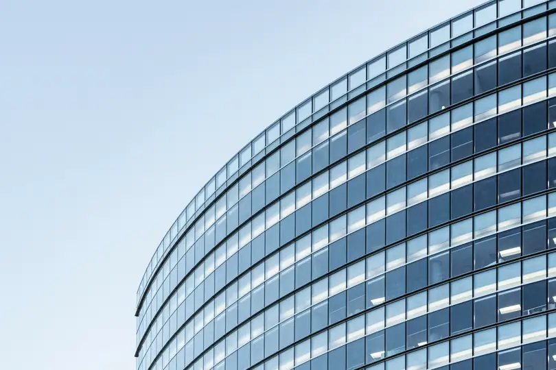 The curved glass face of an office building against the sky