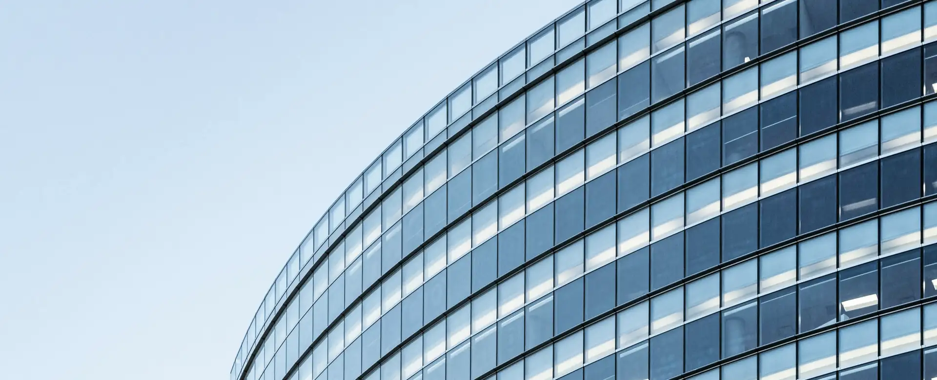 The curved glass face of an office building against the sky