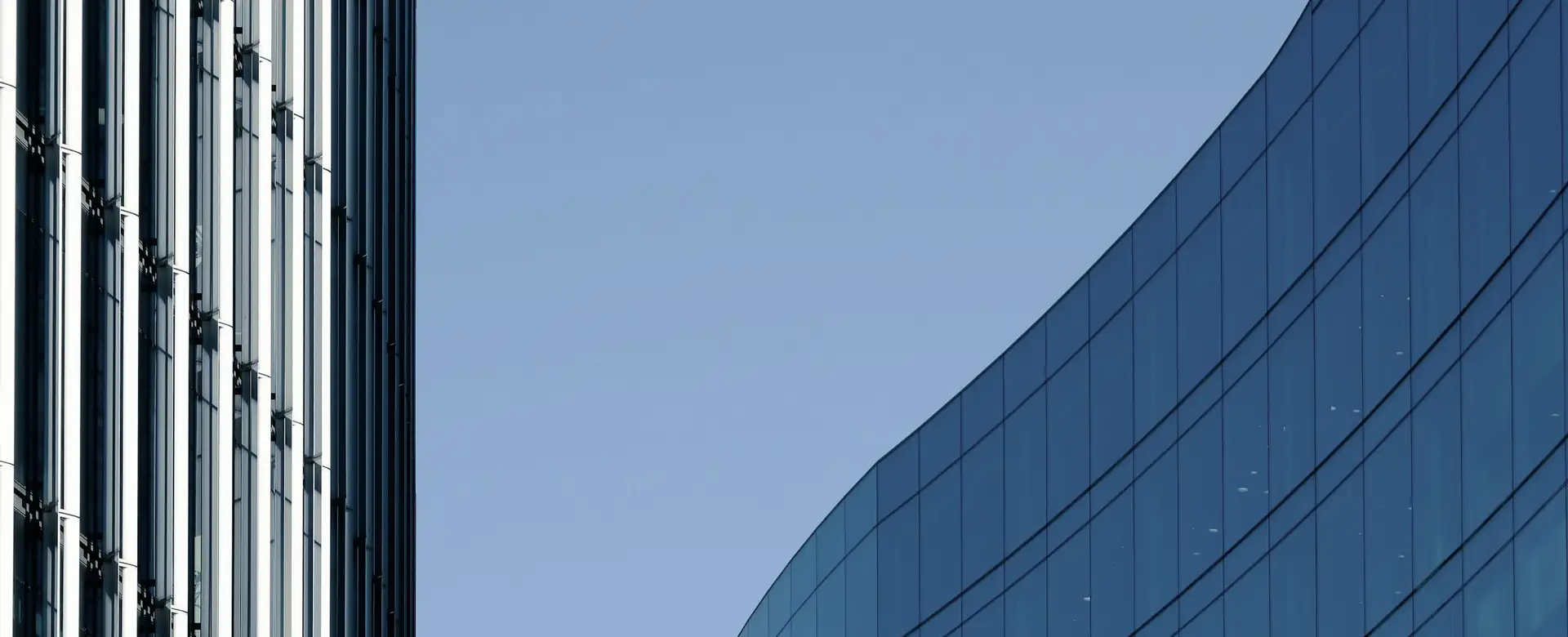 A curved blue glass wall beside a tall tower