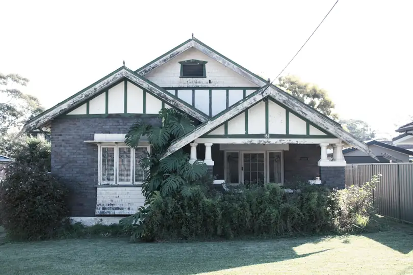 A brick bungalow with a gabled roof behind a garden