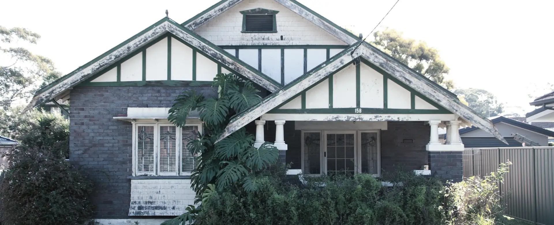 A brick bungalow with a gabled roof behind a garden