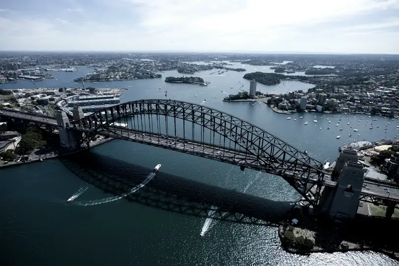 A steel arch bridge and harbour seen from the air