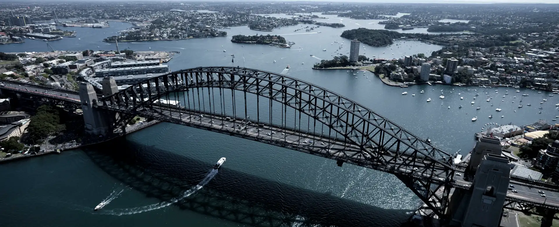 A steel arch bridge and harbour seen from the air