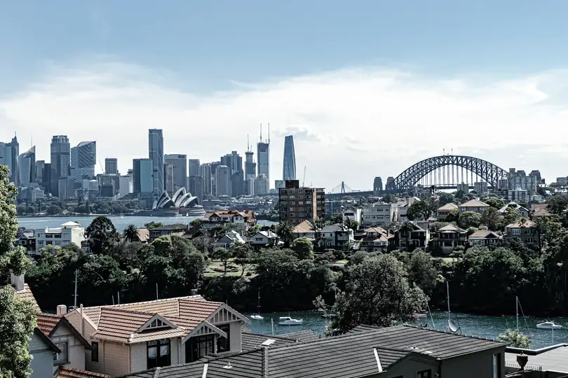 Suburban rooftops with a city skyline and a bridge in the distance