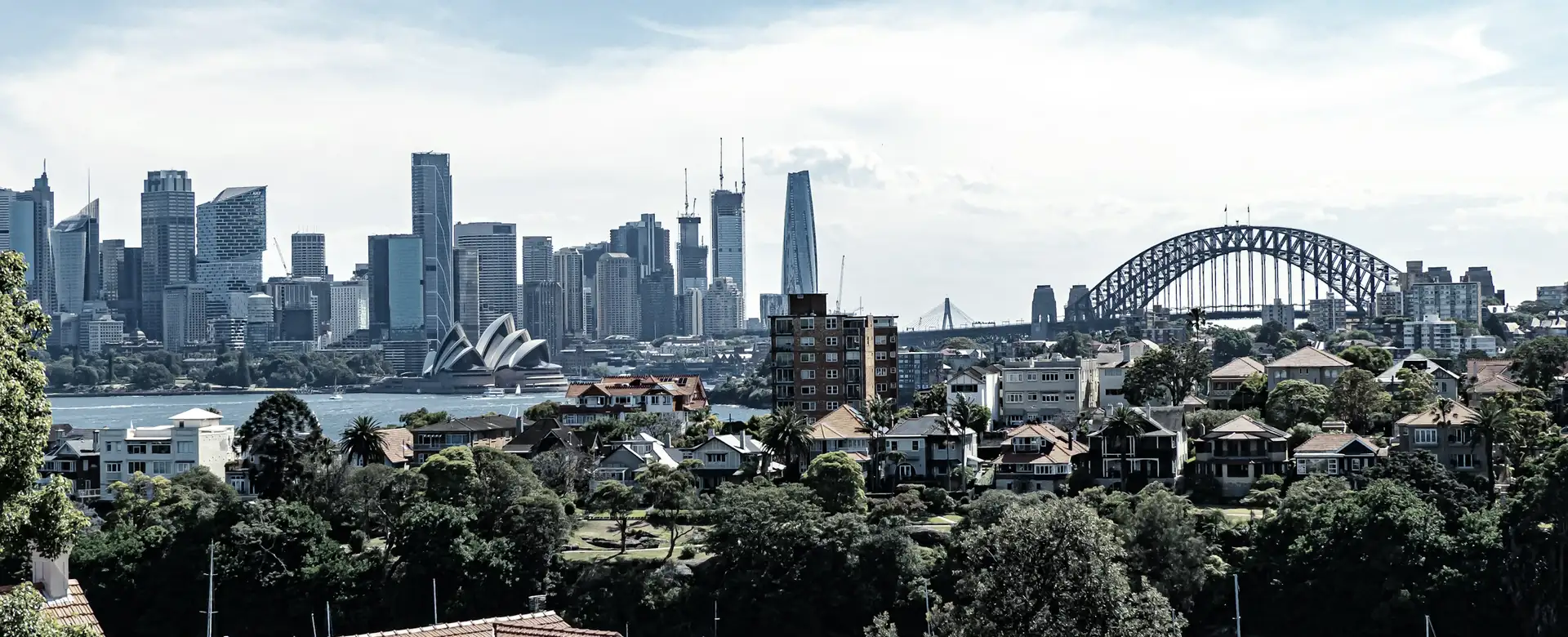 Suburban rooftops with a city skyline and a bridge in the distance