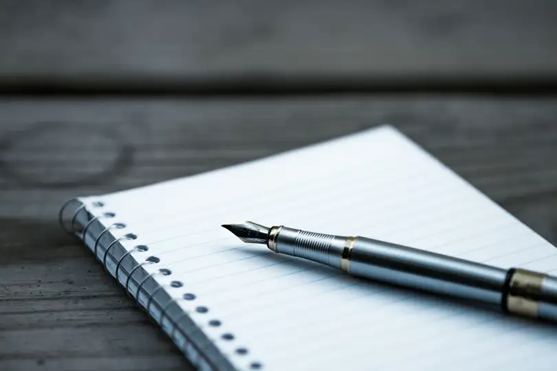A fountain pen resting on an open notebook