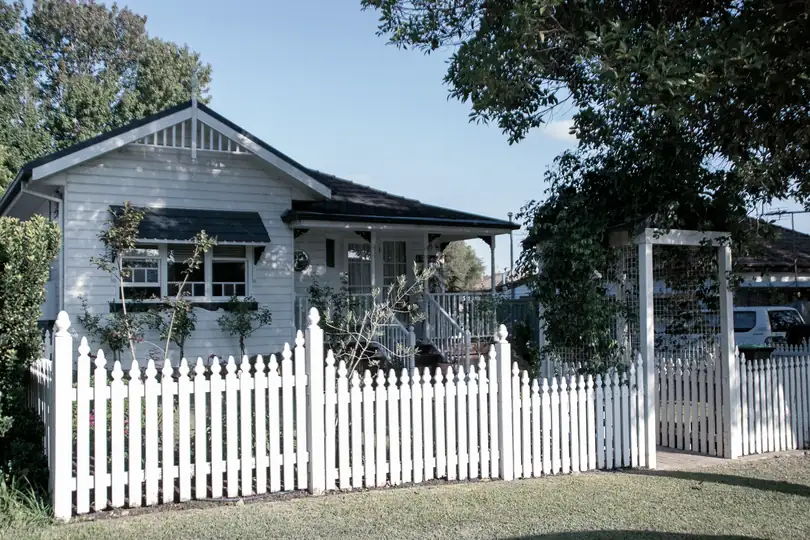 A weatherboard house behind a white picket fence