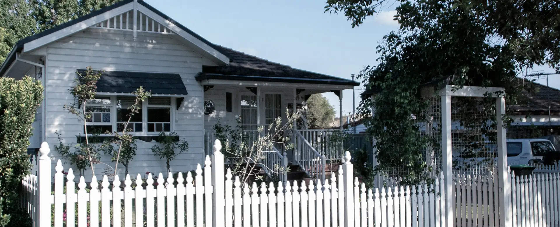 A weatherboard house behind a white picket fence