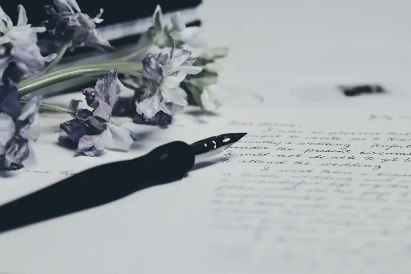 A pen and dried flowers lying on a handwritten page