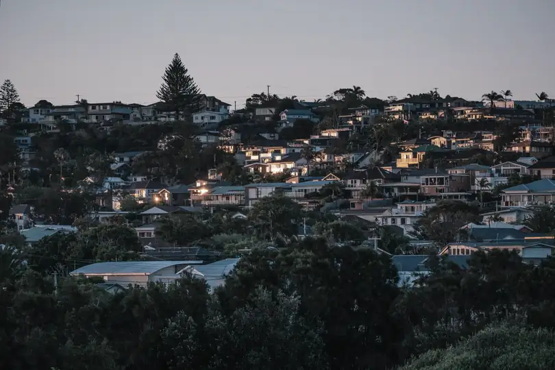 Houses on a hillside at dusk with their lights on