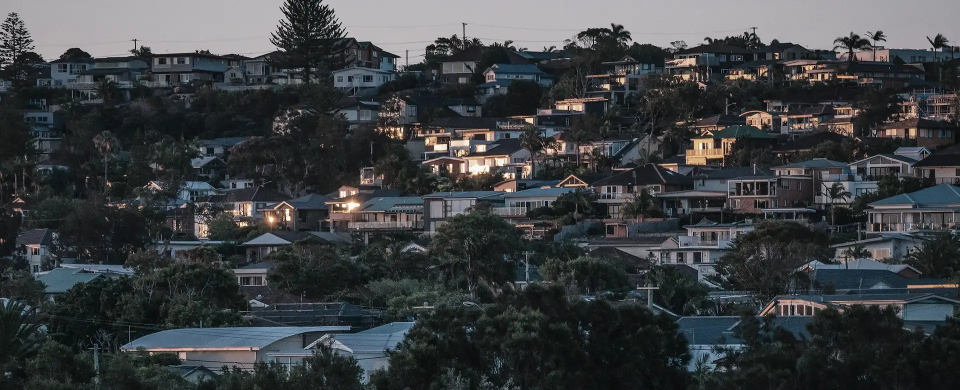 Houses on a hillside at dusk with their lights on