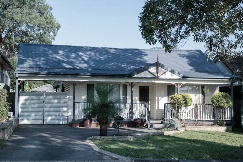 A single-storey house with a blue roof and a front lawn