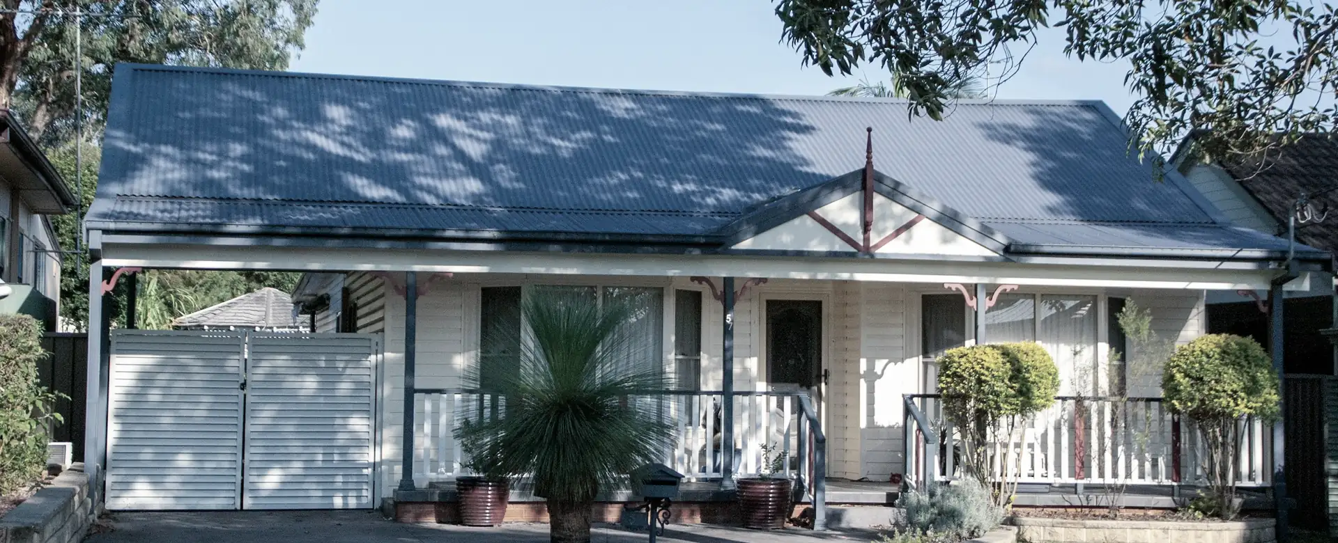 A single-storey house with a blue roof and a front lawn