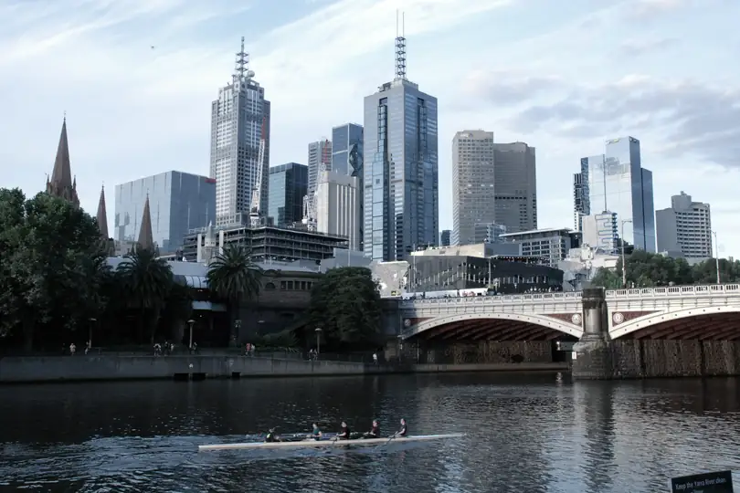 A stone arch bridge over a river with city towers behind