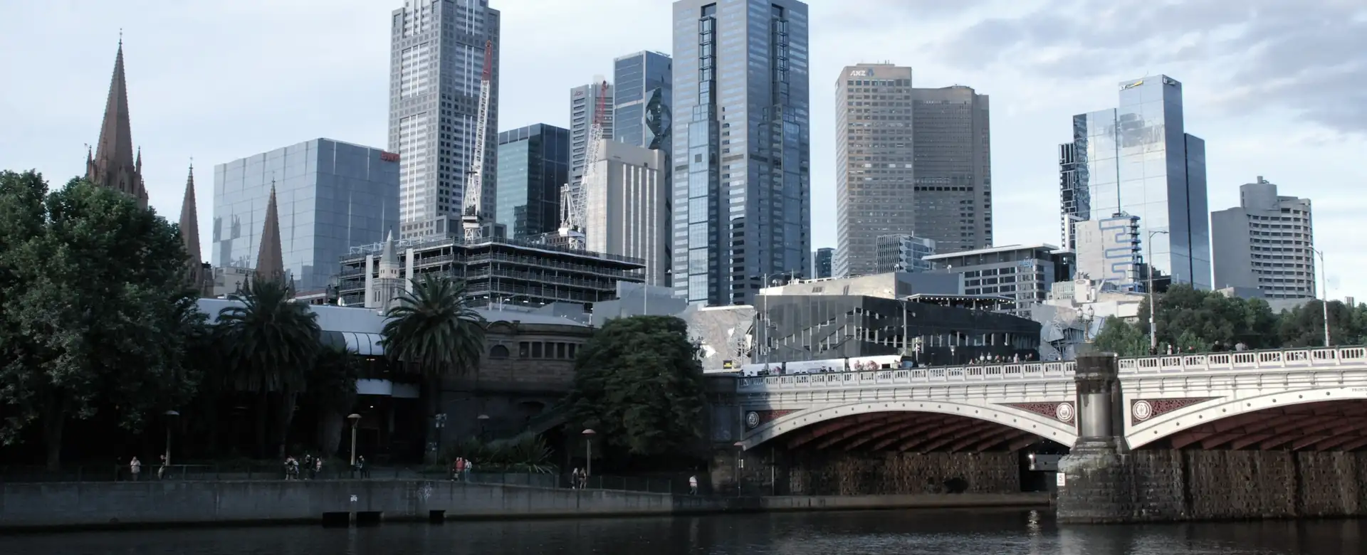A stone arch bridge over a river with city towers behind